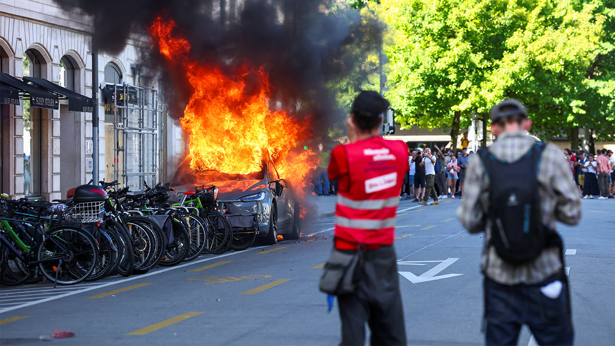 ANTI-G7 PROTESTS TURN VIOLENT IN GENEVA AS DEMONSTRATORS TORCH TESLA VEHICLE AND ATTACK UNITED NATIONS OFFICE